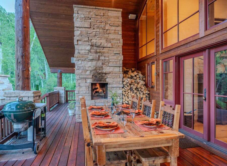 Experience outdoor living at its finest with this stunning covered deck, featuring a cozy stone fireplace and a spacious dining area perfect for entertaining.