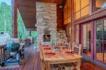 Experience outdoor living at its finest with this stunning covered deck, featuring a cozy stone fireplace and a spacious dining area perfect for entertaining.