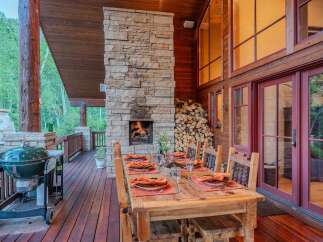 Experience outdoor living at its finest with this stunning covered deck, featuring a cozy stone fireplace and a spacious dining area perfect for entertaining.