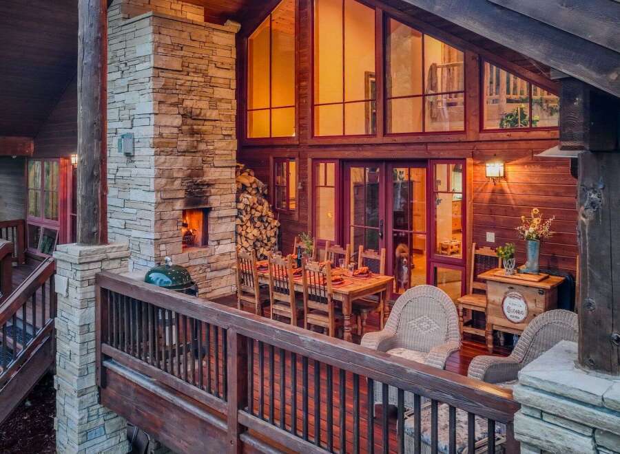 Experience luxurious outdoor living with this stunning deck featuring a stone fireplace and a spacious dining area perfect for entertaining.