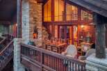 Experience luxurious outdoor living with this stunning deck featuring a stone fireplace and a spacious dining area perfect for entertaining.
