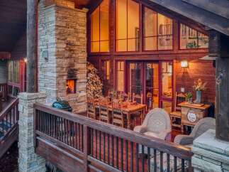 Experience luxurious outdoor living with this stunning deck featuring a stone fireplace and a spacious dining area perfect for entertaining.