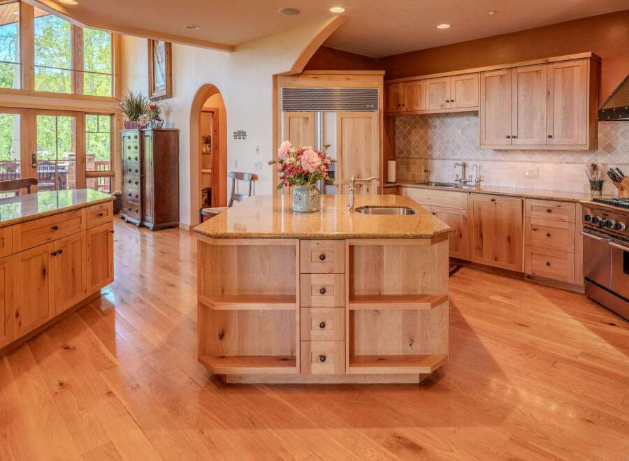 Experience luxury in this stunning kitchen featuring custom light wood cabinetry and a large granite-topped island with a built-in sink.