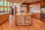 Experience luxury in this stunning kitchen featuring custom light wood cabinetry and a large granite-topped island with a built-in sink.