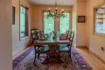 Experience elegant dining in this beautifully appointed dining room, featuring a large wooden table set for ten with vibrant orange napkins and clear glassware.
