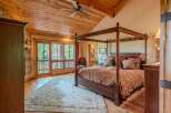 Experience rustic luxury in this stunning bedroom featuring a grand four-poster bed adorned with plush pillows and a richly patterned comforter.