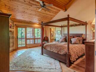 Experience rustic luxury in this stunning bedroom featuring a grand four-poster bed adorned with plush pillows and a richly patterned comforter.