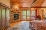 Experience rustic charm in this inviting bedroom featuring a stunning stone fireplace and a natural wood ceiling.