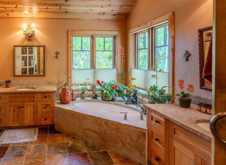 Indulge in relaxation in this luxurious bathroom featuring a spacious soaking tub surrounded by lush greenery and natural light.