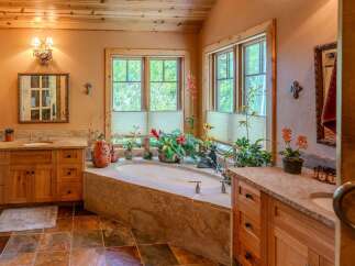 Indulge in relaxation in this luxurious bathroom featuring a spacious soaking tub surrounded by lush greenery and natural light.