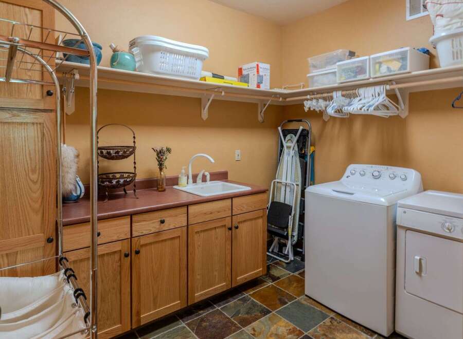 This spacious laundry room features ample storage with overhead shelving and custom wood cabinetry.