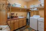 This spacious laundry room features ample storage with overhead shelving and custom wood cabinetry.