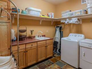 This spacious laundry room features ample storage with overhead shelving and custom wood cabinetry.