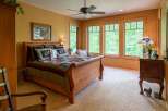 Experience serene living in this charming bedroom featuring a cozy sleigh bed adorned with a beautiful quilt.