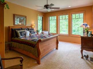 Experience serene living in this charming bedroom featuring a cozy sleigh bed adorned with a beautiful quilt.