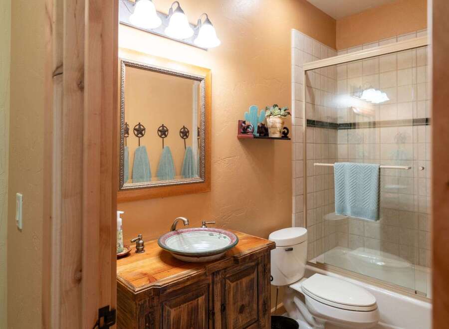 This rustic bathroom features a charming wooden vanity with a decorative vessel sink and a unique star-shaped towel rack above the mirror.