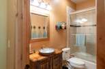 This rustic bathroom features a charming wooden vanity with a decorative vessel sink and a unique star-shaped towel rack above the mirror.