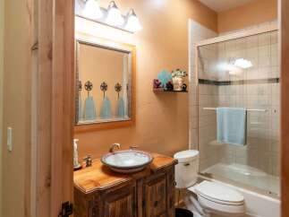 This rustic bathroom features a charming wooden vanity with a decorative vessel sink and a unique star-shaped towel rack above the mirror.