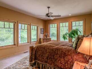 Experience serene living in this charming bedroom, featuring a cozy bed adorned with a rich paisley comforter and a decorative bed skirt.