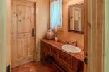 This charming bathroom features a rustic wooden vanity with a white oval sink and antique-style faucets.