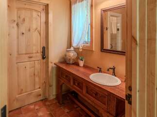 This charming bathroom features a rustic wooden vanity with a white oval sink and antique-style faucets.