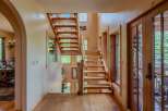 Experience rustic charm in this inviting entryway featuring a beautiful wooden staircase and natural light streaming through large windows.