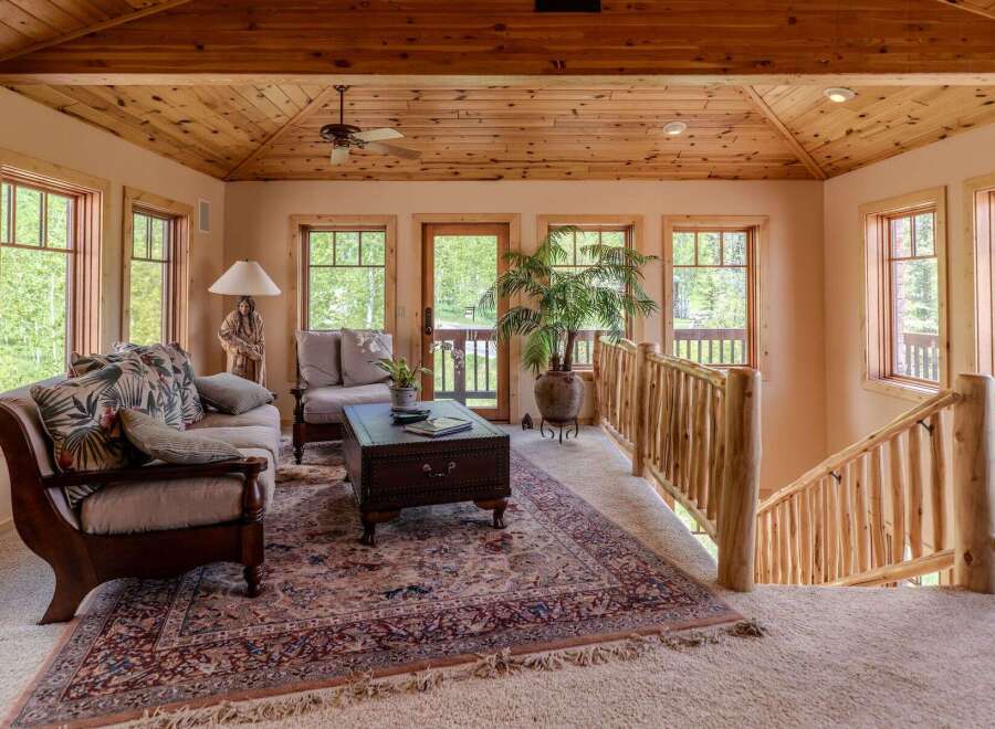 Experience rustic charm in this inviting living space, featuring a cozy seating area with plush cushions and a traditional patterned rug.