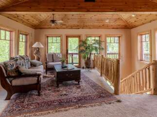 Experience rustic charm in this inviting living space, featuring a cozy seating area with plush cushions and a traditional patterned rug.