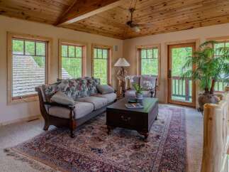 Experience rustic charm in this inviting living room, featuring a floral-patterned sofa and a traditional rug.