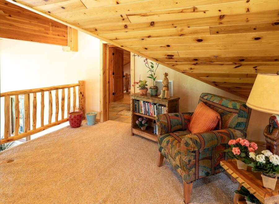 Experience rustic charm in this cozy loft space, featuring a natural wood railing and a warm, inviting armchair perfect for relaxation.