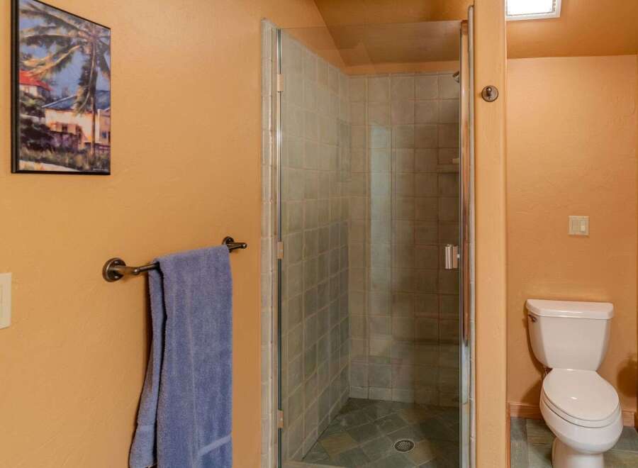 This bathroom features a spacious glass-enclosed shower with tiled walls and a tiled floor, perfect for a refreshing start to your day.