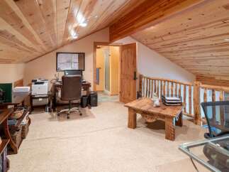 Discover this charming attic office space, featuring a rustic wooden ceiling and a cozy work area.