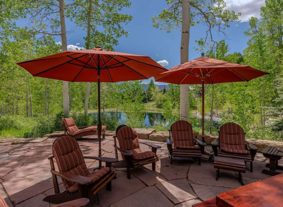 Enjoy the serene mountain views from this stunning outdoor patio, complete with comfortable Adirondack chairs and large umbrellas for shade.