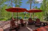 Enjoy the serene mountain views from this stunning outdoor patio, complete with comfortable Adirondack chairs and large umbrellas for shade.