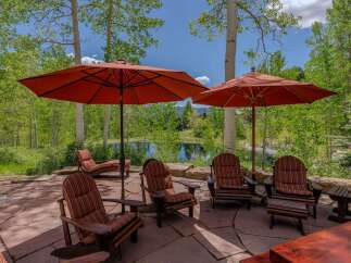 Enjoy the serene mountain views from this stunning outdoor patio, complete with comfortable Adirondack chairs and large umbrellas for shade.
