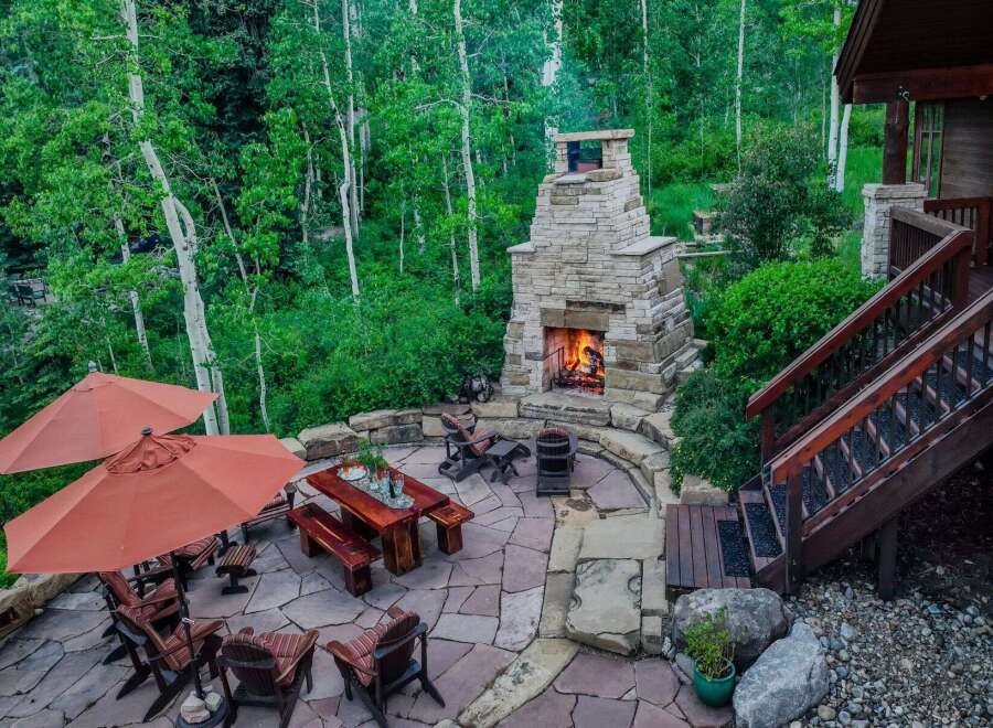 Experience outdoor living at its finest with this stunning patio featuring a grand stone fireplace, perfect for cozy evenings.