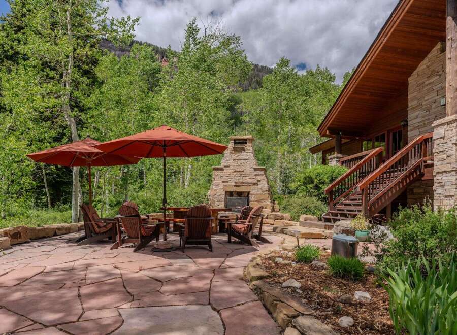 Enjoy the serene mountain setting from this stunning outdoor living space, complete with a large stone fireplace and comfortable Adirondack chairs.
