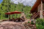 Enjoy the serene mountain setting from this stunning outdoor living space, complete with a large stone fireplace and comfortable Adirondack chairs.