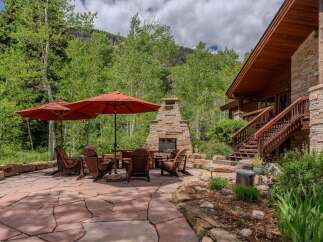 Enjoy the serene mountain setting from this stunning outdoor living space, complete with a large stone fireplace and comfortable Adirondack chairs.