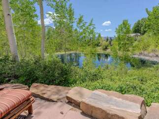 Escape to this serene oasis featuring a tranquil pond surrounded by lush greenery and mature aspen trees.