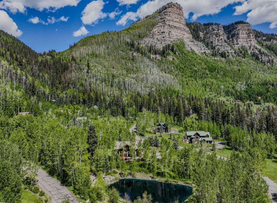 Nestled amidst a lush forest and towering mountains, this property offers a serene escape with a private pond and multiple charming homes.