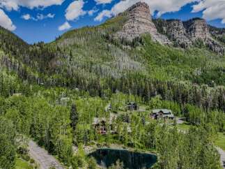 Nestled amidst a lush forest and towering mountains, this property offers a serene escape with a private pond and multiple charming homes.