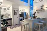 This modern kitchen features sleek white cabinetry, a marble backsplash, and stainless steel appliances, creating a bright and functional space.