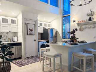 This modern kitchen features sleek white cabinetry, a marble backsplash, and stainless steel appliances, creating a bright and functional space.