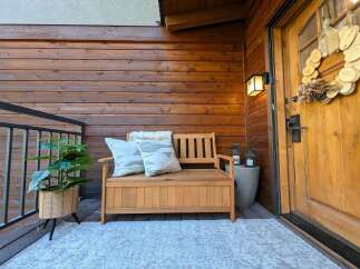 Enhance your home's curb appeal with this inviting porch setup, featuring a charming wooden bench with storage, perfect for outdoor seating and organization.