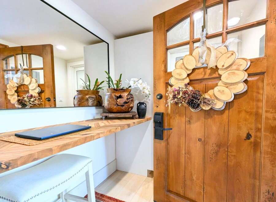 Welcome guests into this charming entryway featuring a rustic wooden door adorned with a unique wood slice wreath.