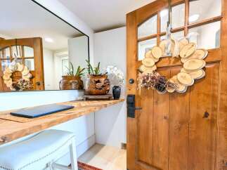Welcome guests into this charming entryway featuring a rustic wooden door adorned with a unique wood slice wreath.