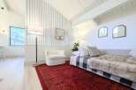 This bright and airy living space features a vaulted ceiling with exposed beams and a unique slatted wall accent.