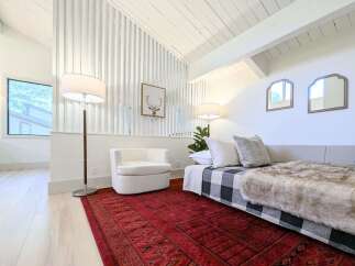 This bright and airy living space features a vaulted ceiling with exposed beams and a unique slatted wall accent.
