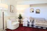 This cozy living space features a comfortable white armchair and a stylish daybed adorned with a buffalo check blanket and a plush faux fur throw.